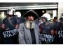Bezdomny stojący na tle kordonu policji, podczas protestów pracowników Ministerstwa Finansów przed Ministerstwem Finansów w Atenach. Grecja, 27 września 2011